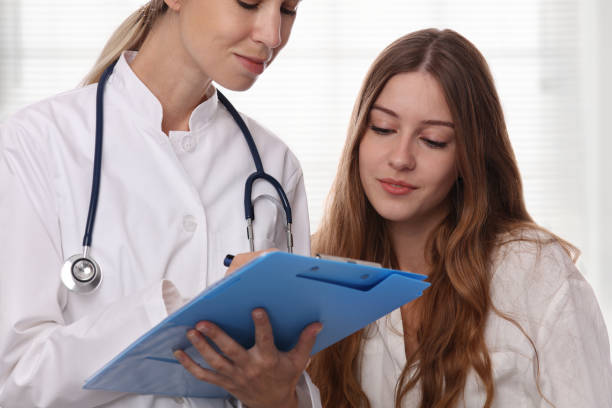Smiling female doctor showing to teenage patient test results. Medical consultation stock photo