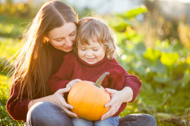 istock Mother and child choosing pumpkins for jack-o-lantern. 857605898