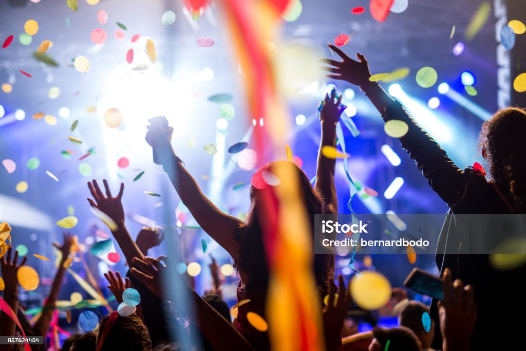 Confetti and party Crowd of people raising their hands in the air on a music festival. Crowd of People Stock Photo