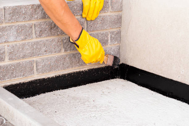 worker applies bitumen mastic on the foundation