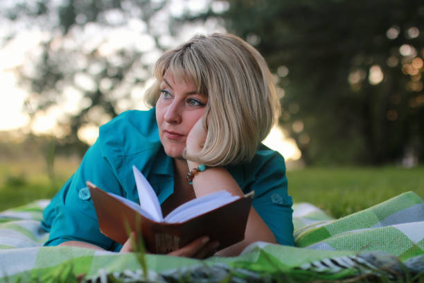 istock woman in park with book on the grass 857630308
