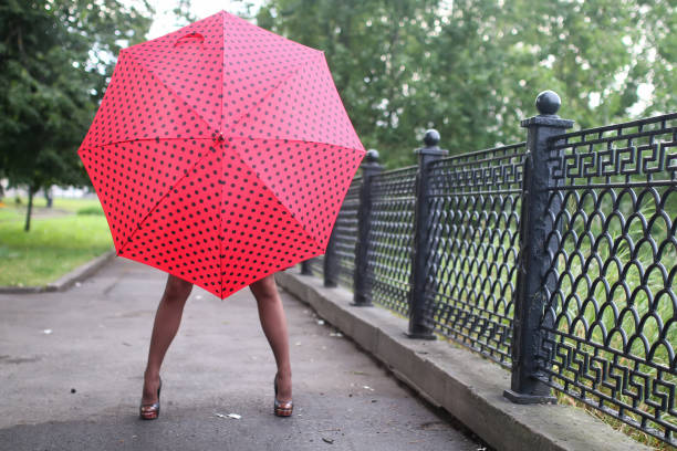 istock woman with umbrella red on street tree 857634102