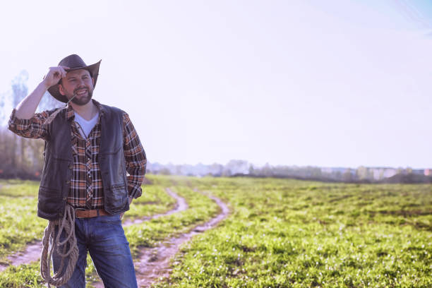 istock Cowboy standing in a field at sunset 857634410