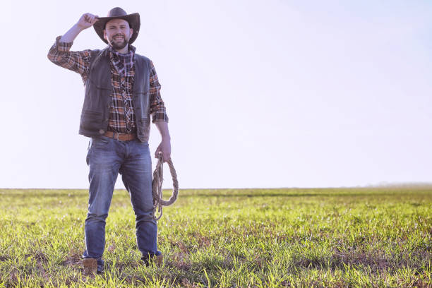 istock Cowboy standing in a field at sunset 857634512