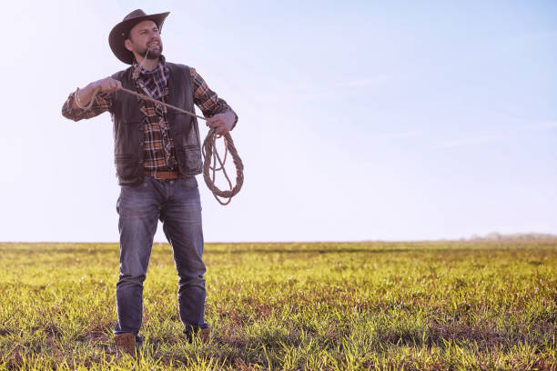 istock Cowboy standing in a field at sunset 857634532