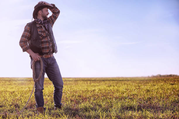 istock Cowboy standing in a field at sunset 857634552
