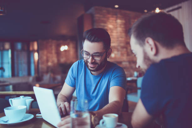 istock Two Handsome Friends Drinking Coffee and Surfing the Net In Cafe Restaurant 857638156
