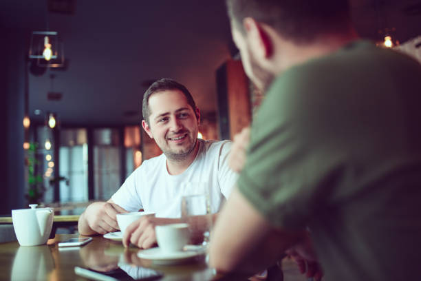 zwei lächelnde freunden kaffee trinken und geselligkeit in einem cafe - espresso men coffee shop drinking stock-fotos und bilder