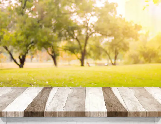 Photo of Empty old rustic wood plank table top with blur forest tree with sunlight,Autumn fall backgorund,Mock up for display or montage of product,banner for advertise on online.