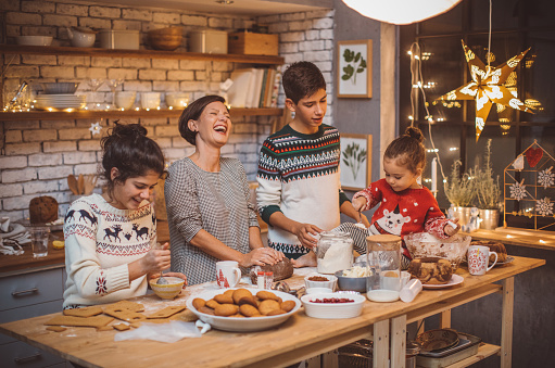 Mother with children in kitchen preparing Christmas cakes
