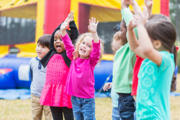 istock Multi-ethnic children playing in park, by bounce house 857643038