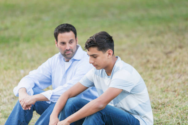 istock Father sitting with serious teenage boy 857645400