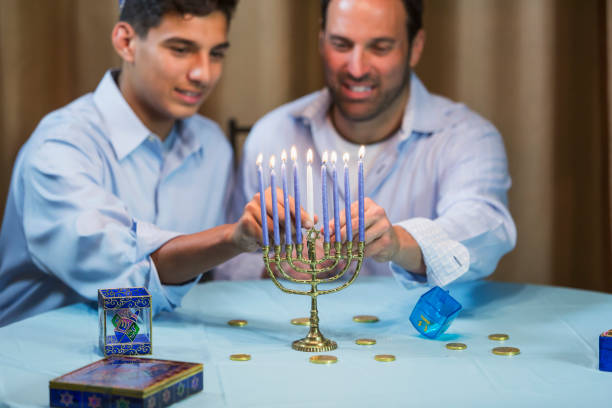 istock Father and teenage son lighting menorah 857645456