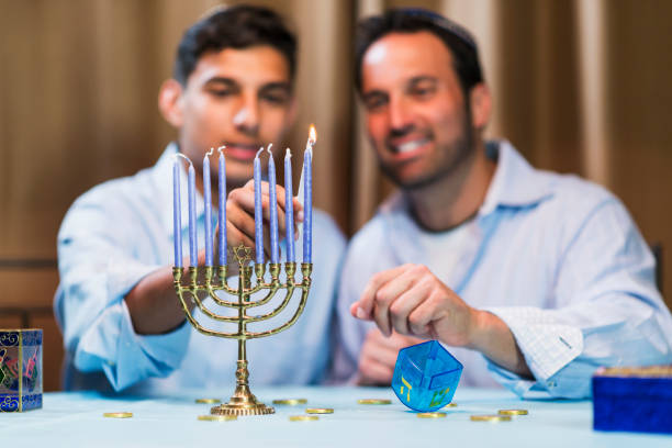 istock Father and teenage son lighting menorah 857645632