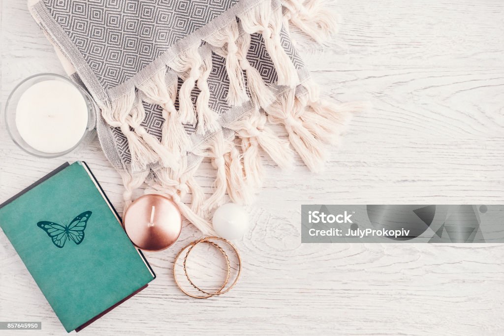 Fall and winter woman fashion still life Fall and winter woman fashion still life on white wooden table. Cozy wool scarf, notebook, rose gold candle, jewelry. Copy space, blogging concept Book Stock Photo