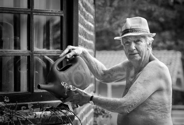 senior man watering plants gardening - portrait black and white senior men wisdom imagens e fotografias de stock