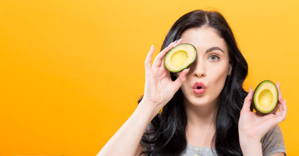 istock Happy young woman holding avocado halves 857675048