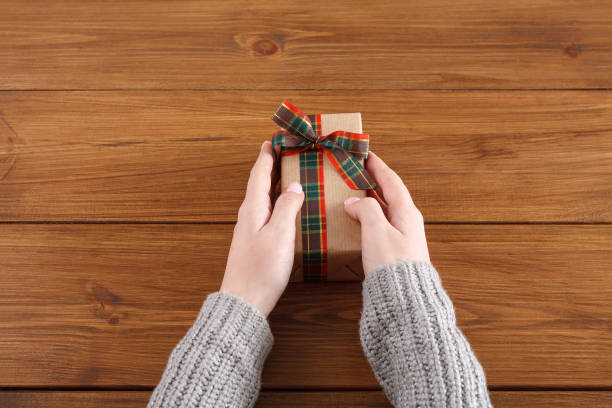 istock Woman's hands give christmas gift in present box 857693268