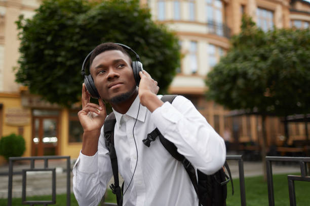 istock African student at break listening music at park 857700548