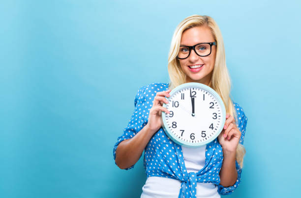 istock Woman holding clock showing nearly 12 857701606