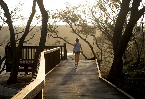 A girl walks on the boardwalk at the Gorge walk on North Stradbroke Island at Sunset