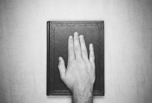 本は、聖書の宣誓に手をマンします。トップ ビューのクローズ アップ。黒と白の写真 - man’s hands スト��ックフォトと画像