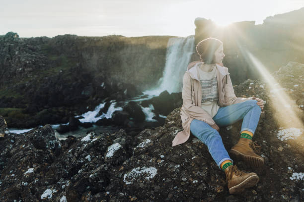 istock Woman sitting near   waterfall in mountains 857716492