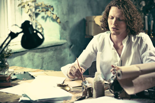 istock Writer at work. Handsome young writer sitting at the table and writing something in his sketchpad 857744458