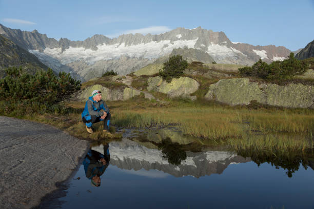 istock In a mountain lake the landscape is reflected. a hiker makes a break 857747108