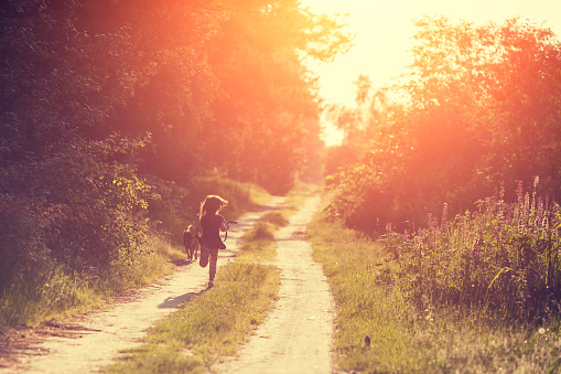 A little girl with a dog runs along a country road