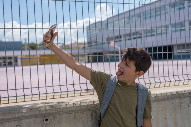 istock Student resting outside a school and playing with a mobile phone 857754490