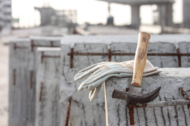 istock Leather safety gloves and hammer on construction working site background 857759068