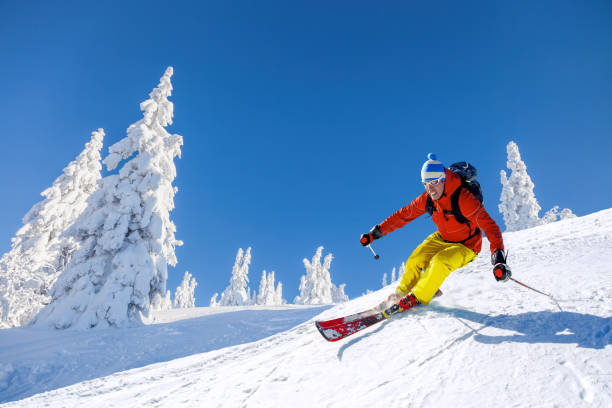 Skier skiing downhill in high mountains against blue sky Skier skiing downhill in high mountains against blue sky skiing photos stock pictures, royalty-free photos & images