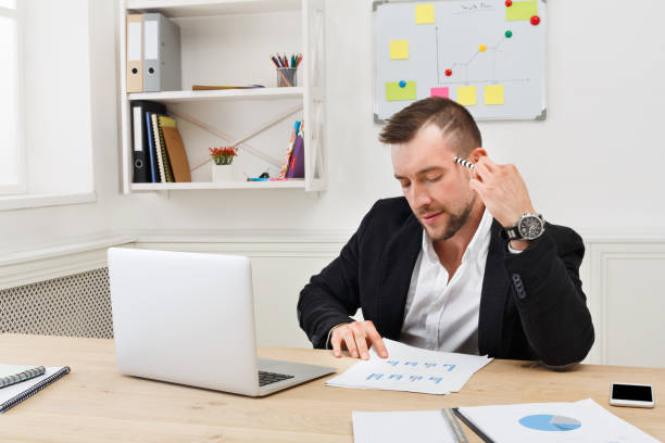 istock Young concentrated businessman read documents in modern white of 857779322