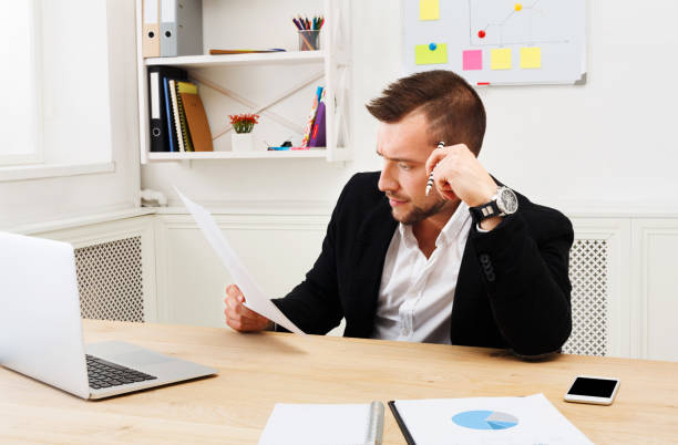 istock Young concentrated businessman read documents in modern white of 857781512