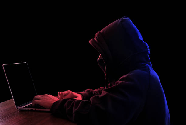 istock Hacker in hoodie working on laptop in the dark hacking secured network 857781820