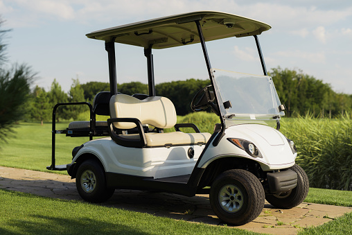 A golfer is driving a golf cart on a beautiful green course