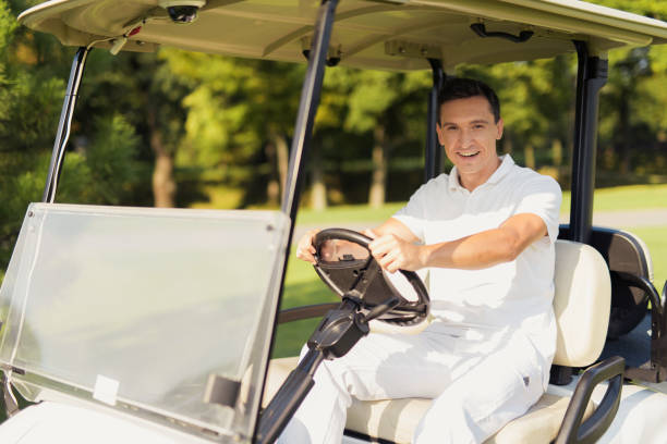 istock A man in a white suit is driving a white golf car and smiling 857783066