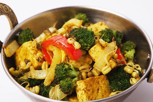 Restaurant vegan dish, tofu stir fry in copper bowl isolated on white. Vegetable mix. Eastern indian local cuisine food.
