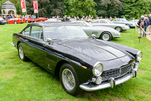 Ferrari 250 GTE series 3 classic Italian coupe Gran Turismo car. The 250 GT/E is fitted with a V12 engine and was  the first large-production four-seat Ferrari built between 1959 and 1963. The car is on display during the 2017 Classic Days event at Schloss Dyck. People in the background are looking at the cars.