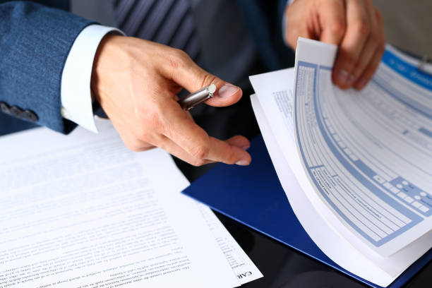 Male arm in suit offer insurance form clipped to pad Male arm in suit offer insurance form clipped to pad and silver pen to sign closeup. Strike a bargain, driver money loss prevention, secure road trip, harmless drive idea, owner protective concept insurance stock pictures, royalty-free photos & images