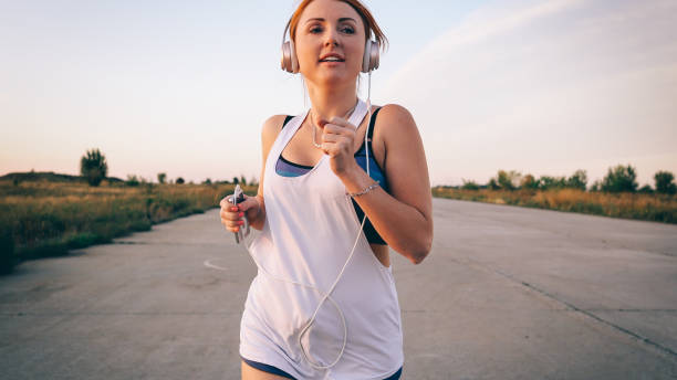 kobieta biegająca i słuchająca muzyki na słuchawkach - lastone therapy audio zdjęcia i obrazy z banku zdjęć