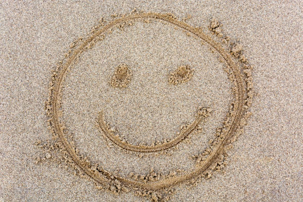 istock A smiley face drawn in the sand from above 857801854