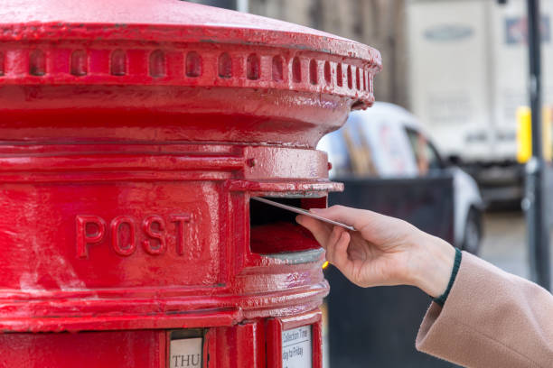 istock Throwing a letter in a red British post box from the side 857806042