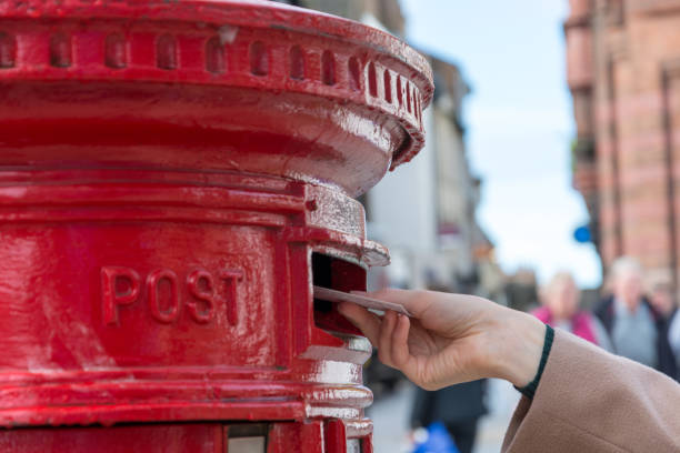 istock Throwing a letter in a red British post box from the side 857806052