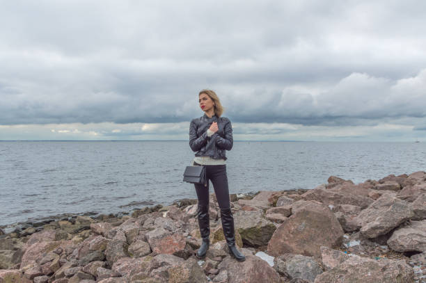 istock a beautiful woman stands on a rocky beach 857813322