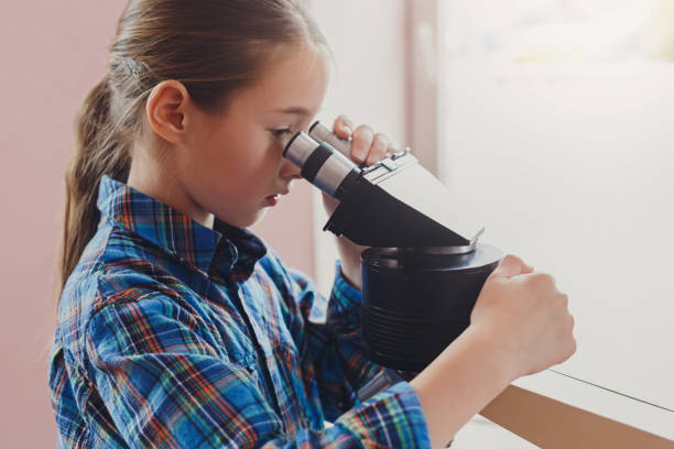 istock Schoolgirl looking in microscope on lesson 857821974