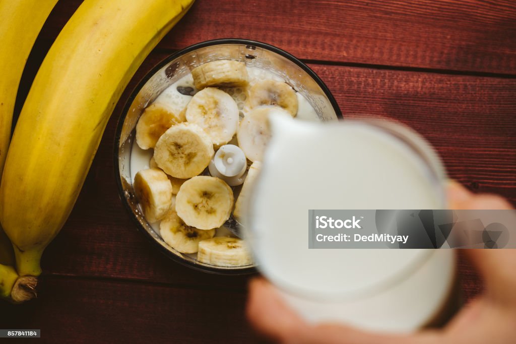 Pouring milk in blender over pieces of bananas, banana smoothie, top view Pouring milk in blender over pieces of bananas. Healthy shake, banana smoothie, top view Blender Stock Photo