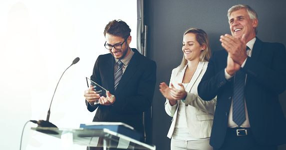 Cropped shot of two corporate businesspeople applauding the recipient of an award during a ceremony