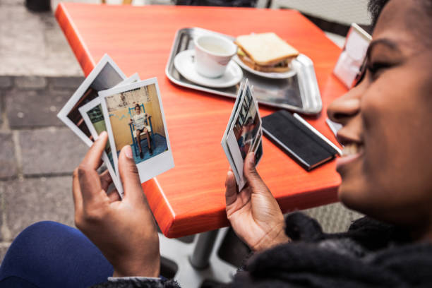 Young woman looking at instant camera photo frames Young woman looking at instant camera photo frames. holding photos stock pictures, royalty-free photos & images